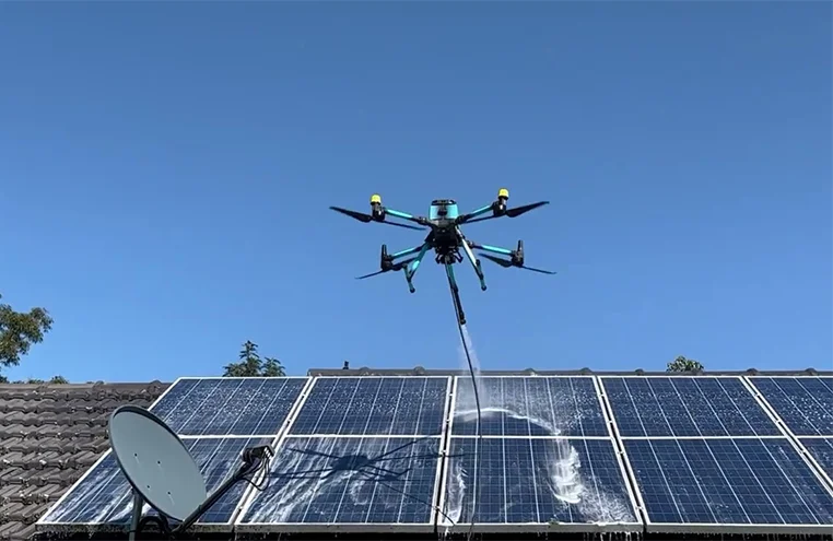 Drone cleaning rooftop solar panels with high-pressure water